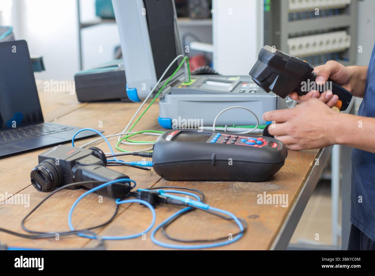 VINKOVCI, CROAZIA, 06.20.2018: Tecnico che lavora con apparecchiature di prova su una scrivania di legno, circondato da vari strumenti elettronici. L'ambientazione è la vetrina Foto Stock