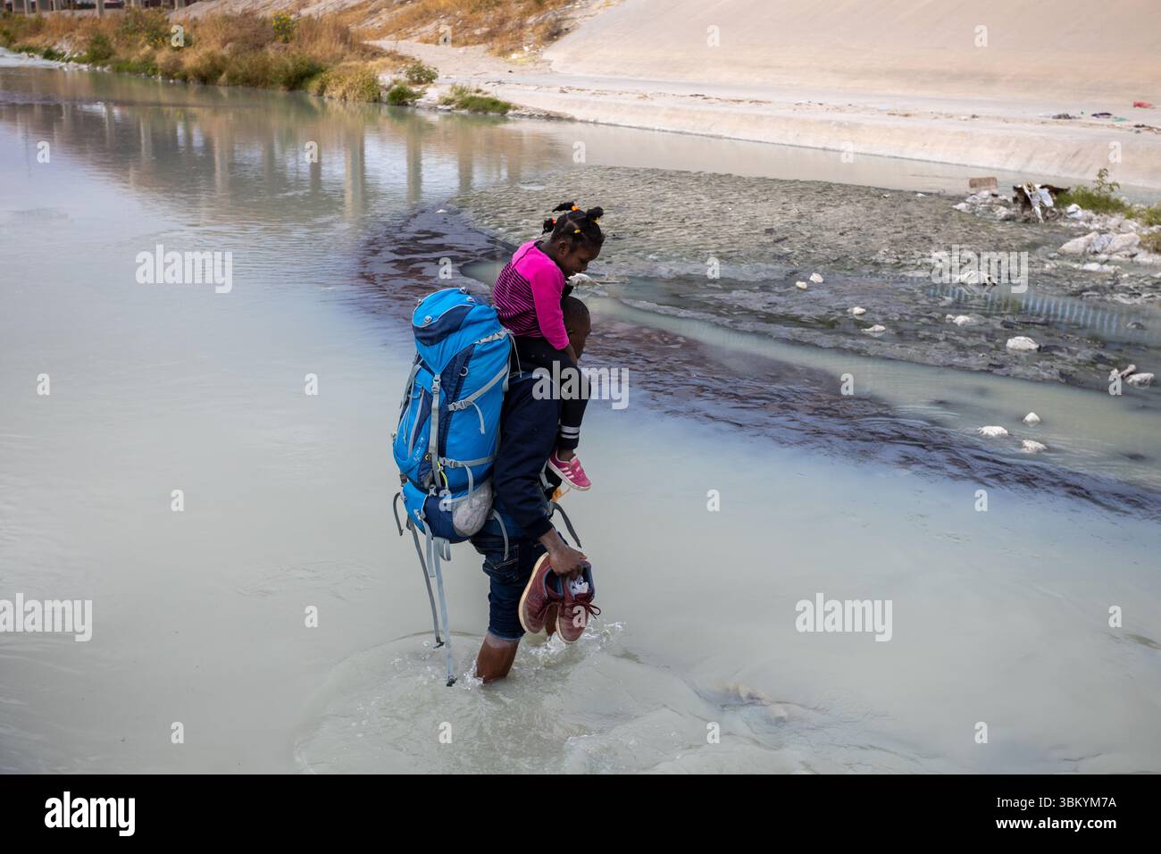 Due adulti assistono un bambino nei pressi di una sponda del fiume Foto Stock