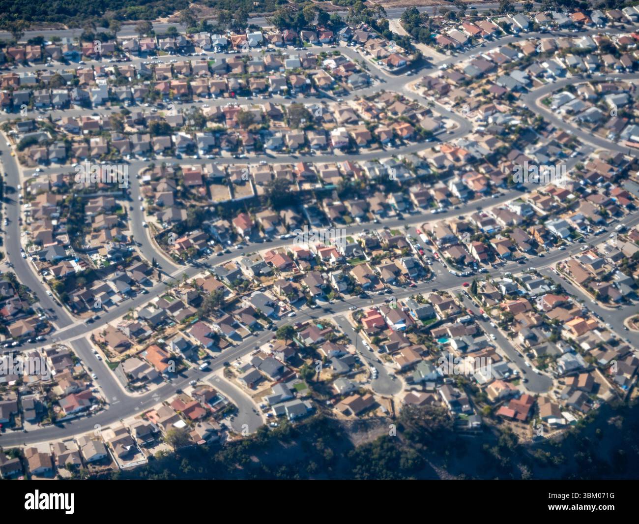 Una vista aerea mostra un quartiere periferico densamente affollato con strade tortuose e case dai vari colori del tetto, che illustrano la pianificazione urbana e la vita residenziale. Foto Stock
