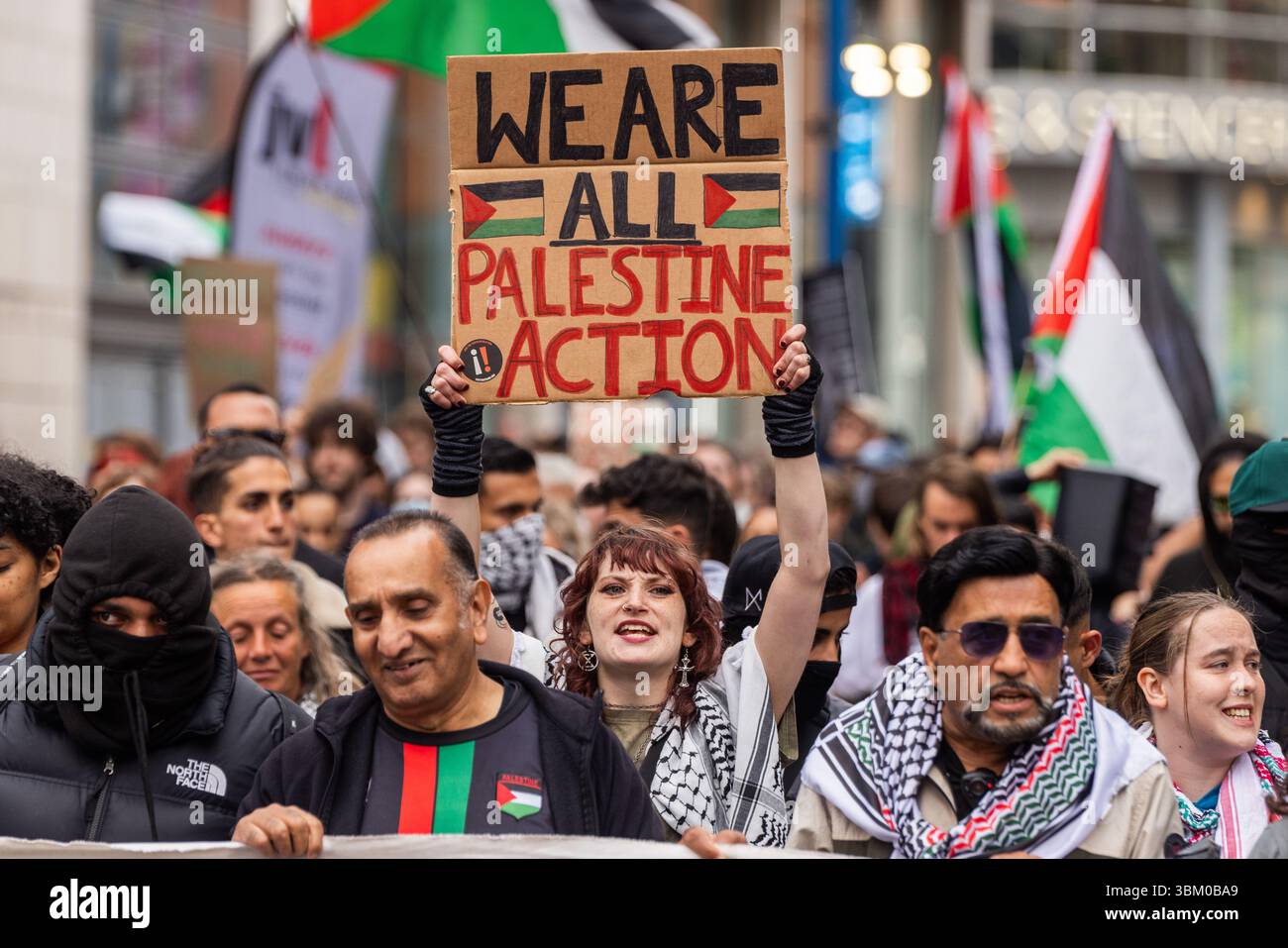 Manchester, Regno Unito. 23 GIUGNO 2025. La persona ha il cartello "We Are All Palestine Action” mentre gli attivisti marciavano e si radunavano in una protesta di emergenza a sostegno del gruppo di azione diretta Palestina Action. Il gruppo ha recentemente fatto notizia in seguito al trasferimento del segretario di Stato per propugnarlo come organizzazione terroristica a seguito dei danni causati a Brize Norton e dei ripetuti tentativi di armistizio di compagnie di armamento. Credito Milo Chandler/Alamy Live News Foto Stock
