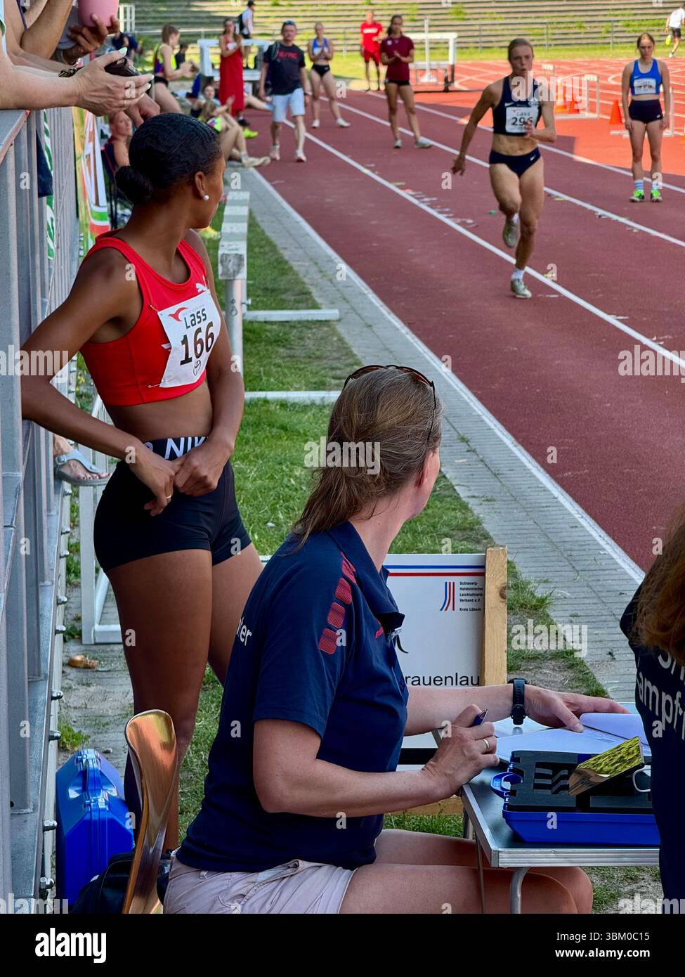 Le atlete gareggiano in una gara di salto su pista e sul campo, con le ufficiali che registrano i risultati Foto Stock