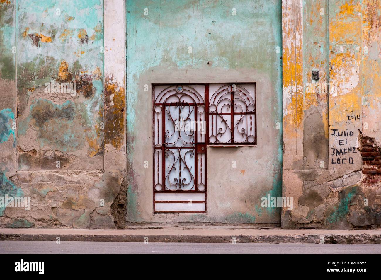 Cuba, l'Avana. Muro dell'Avana vecchia, vernice rosa, verde e gialla. Ferro battuto, cancello e porta. (Solo per uso editoriale). Foto Stock
