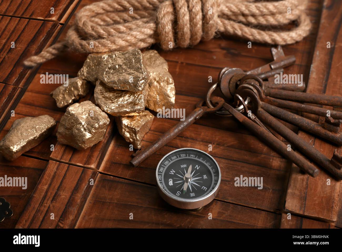 Scatola di legno con attrezzatura da viaggio e pepite dorate su sfondo nero Foto Stock