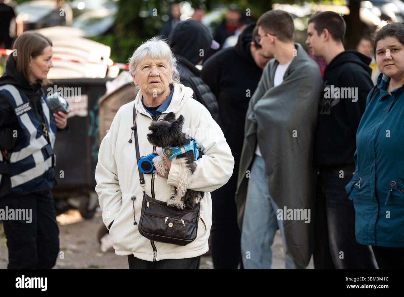 Non esclusiva: Una donna tiene un cane tra le braccia mentre gli equipaggi di emergenza rispondono alle conseguenze di un attacco combinato russo balistico e drone nel SH Foto Stock