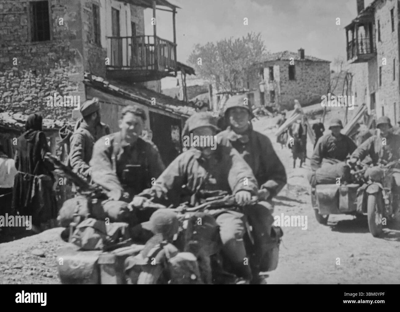 WW2 Screen B&W ancora truppe tedesche delle Leibstandarte SS cavalcano motociclette e Sidecar attraverso una città greca durante l'operazione "Marita", l'invasione tedesca della Grecia. Foto Stock