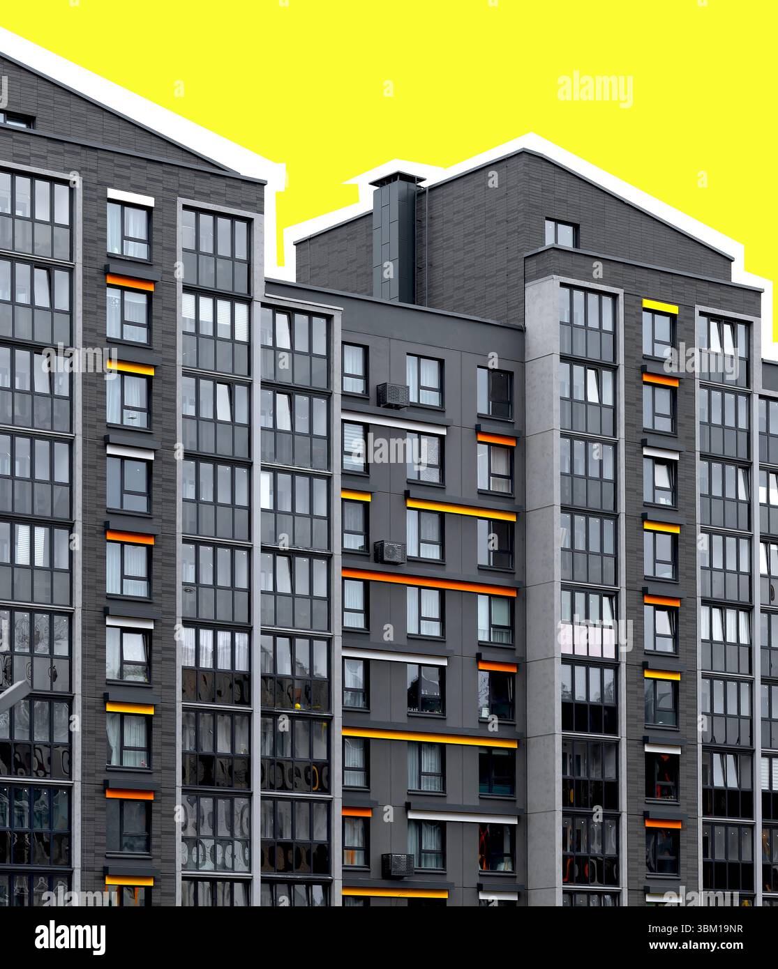 Edificio di appartamenti contemporaneo con accenti luminosi arancioni e gialli su una facciata geometrica. Struttura alta e moderna con finestre in vetro che rappresentano Foto Stock