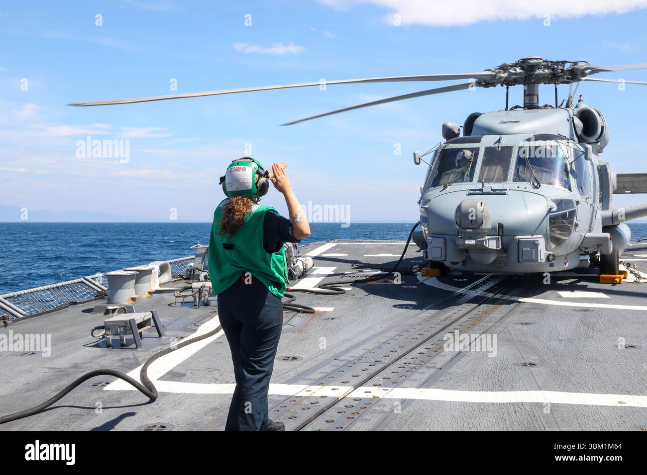250622-N-CV021-1022 Aircrew Survival Equipmentman Airman Noelani Sapp, di Woodbine, Georgia, dà segnali manuali ai piloti all'interno di un elicottero MH-60R Sea Hawk a bordo del cacciatorpediniere missilistico guidato classe Arleigh Burke USS John Finn (DDG 113) a Sagami Wan, 22 giugno. John Finn è schierato in avanti e assegnato al Destroyer Squadron (DESRON) 15, il più grande DESRON della Marina e la principale forza di superficie della 7th Fleet. (Foto della Marina degli Stati Uniti di Alexandria Esteban, specialista della comunicazione di massa di seconda classe) Foto Stock