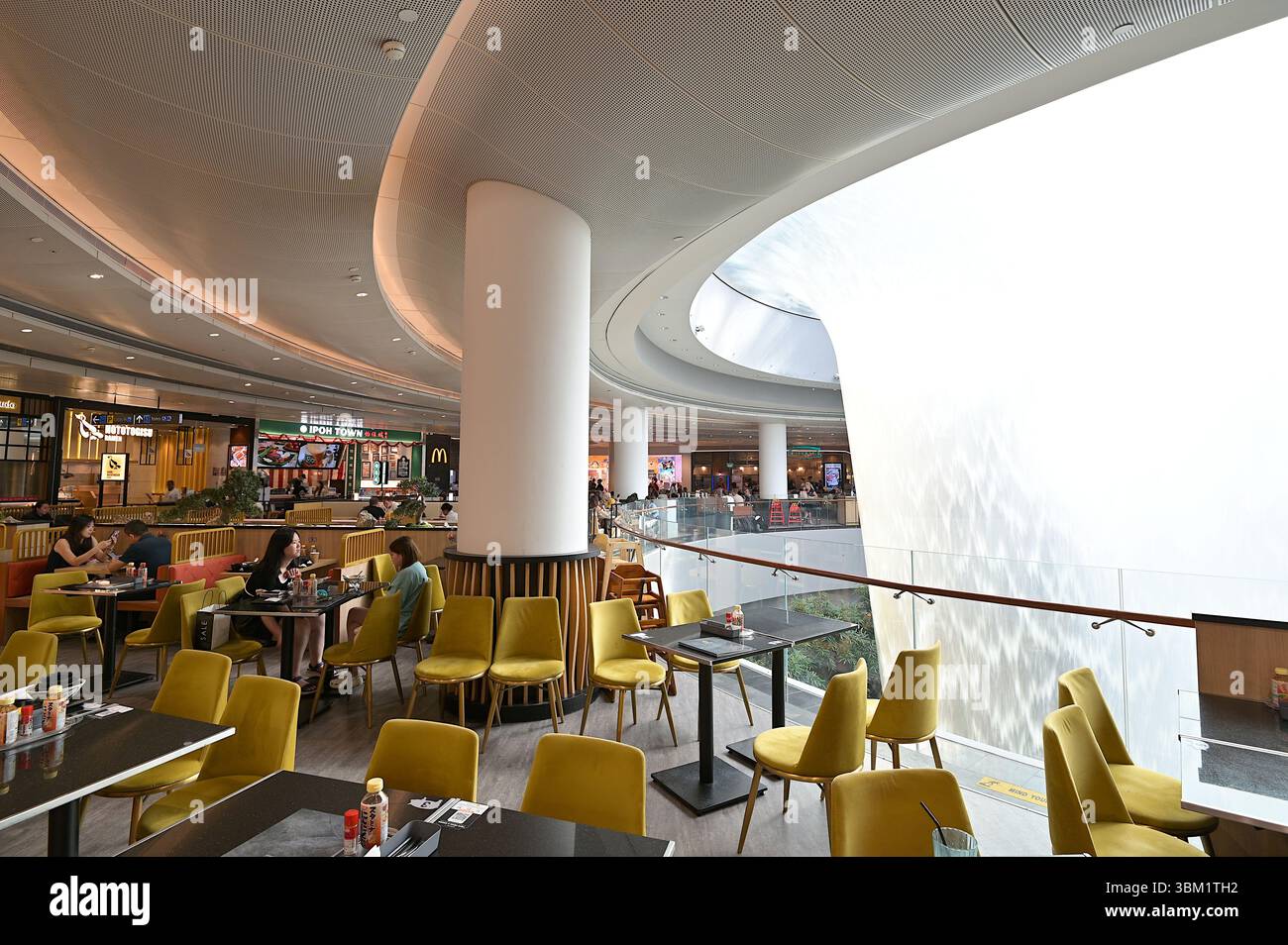Punti ristoro al seminterrato 1 di Jewel all'Aeroporto Changi di Singapore, con il Rain Vortex, la cascata interna più alta del mondo, sulla destra Foto Stock