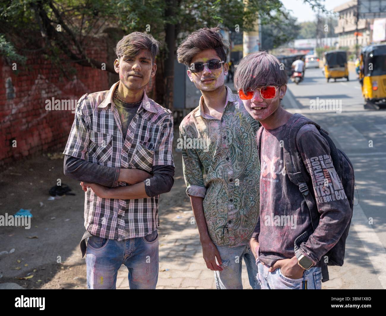 India, Rajasthan, 22 marzo 2025. Tre giovani uomini indiani posano su una strada della città durante il festival Holi, facce colorate di polveri festose, casual urban Foto Stock