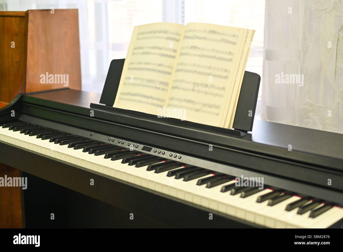 Libro di musica su pianoforte elettronico ad alta tecnologia, che enfatizza l'apprendimento e la composizione. il libro musicale è una risorsa fondamentale per l'apprendimento e la creazione di nuove melodie. con Foto Stock