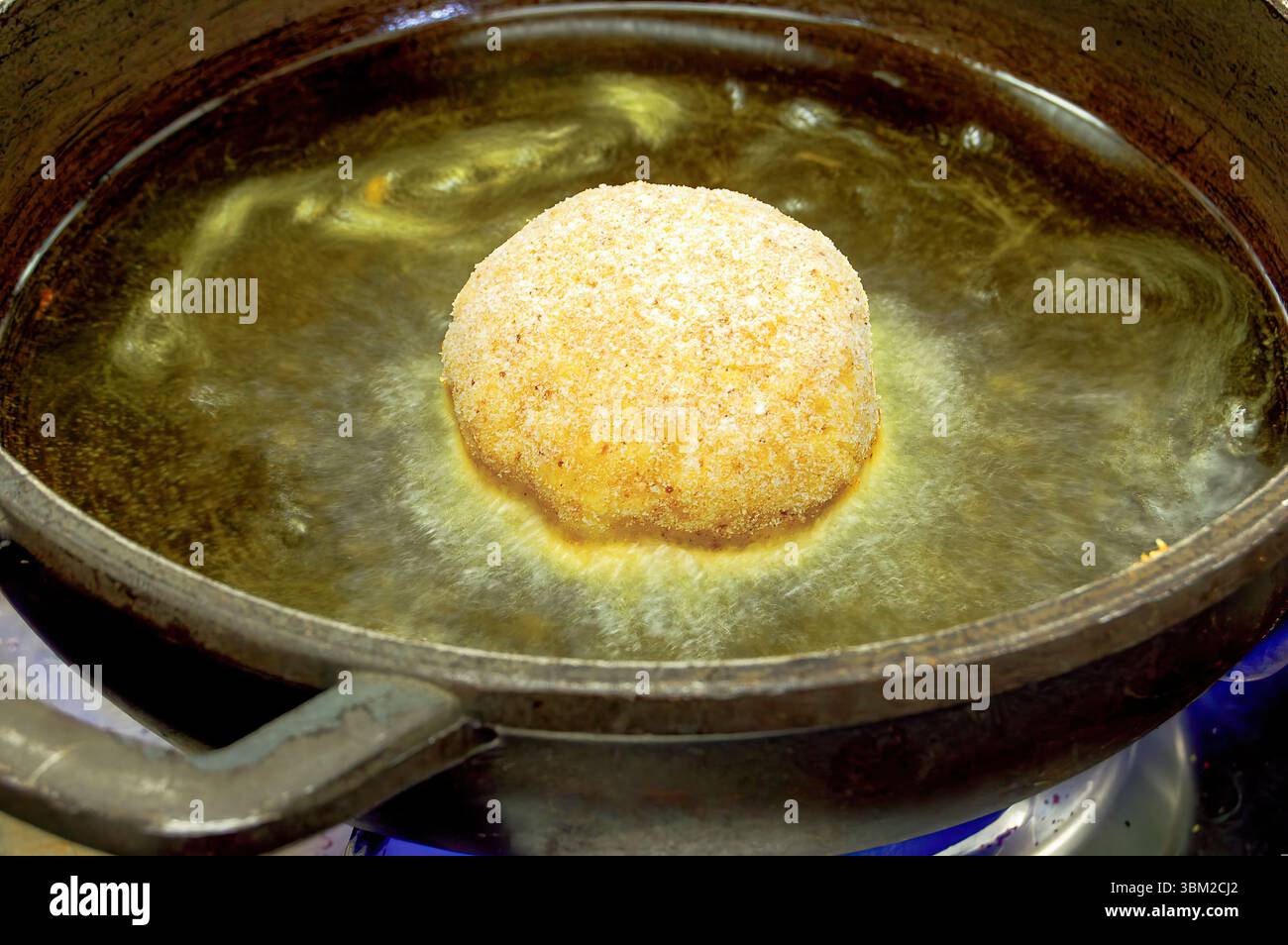 L'arancino, un amato cibo di strada siciliano, presenta riso ripieno con vari ingredienti, impanato e fritto alla perfezione, bollente in olio caldo su un piatto Foto Stock