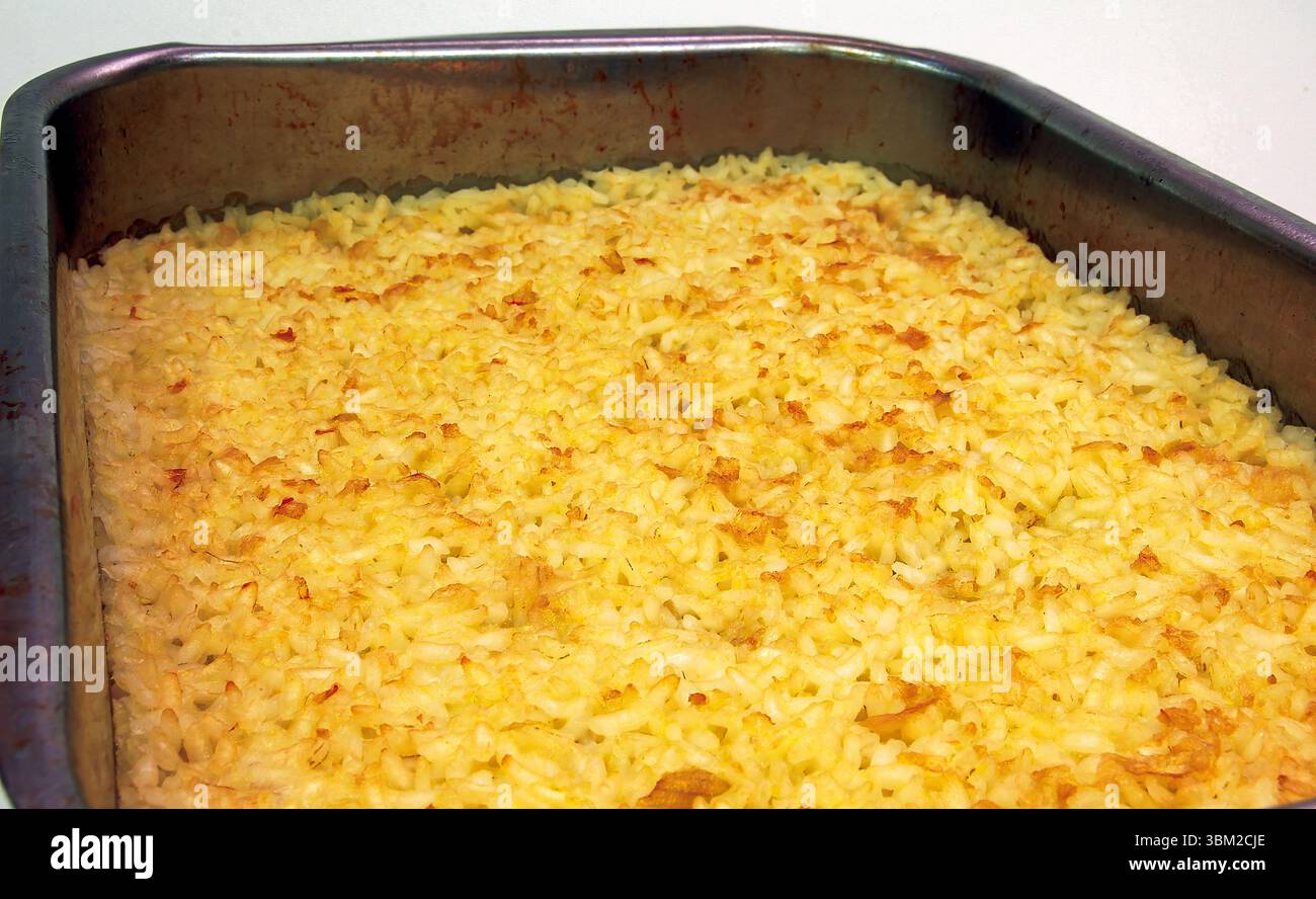 Primo piano di una cottura al gratin di riso dorato in una teglia di metallo, che mostra la sua consistenza croccante e l'aroma invitante, perfetto per blog di cibo, siti Web di ricette, o. Foto Stock