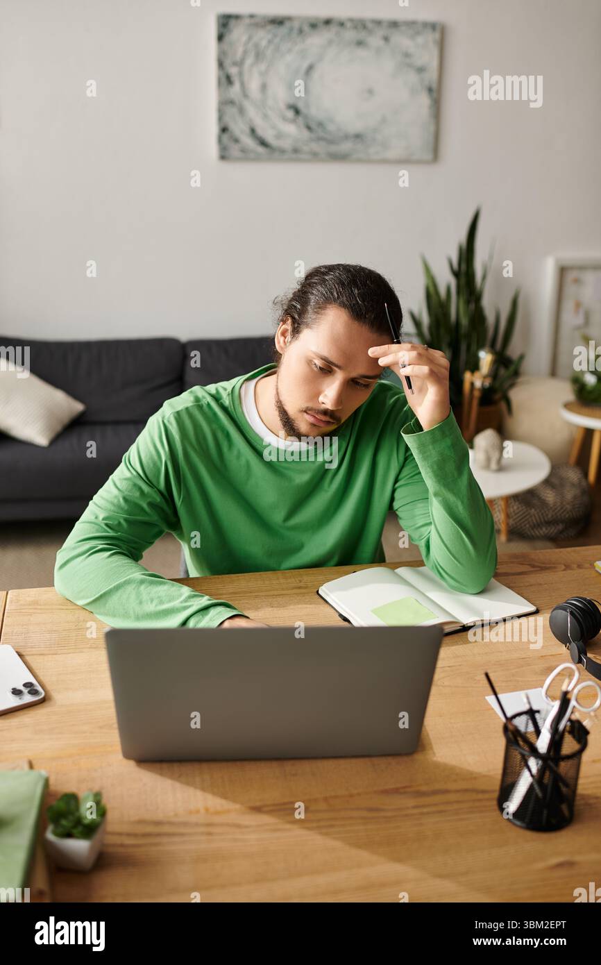 Giovane con un'espressione contemplativa che lavora intensamente alla sua scrivania in un ambiente accogliente. Foto Stock
