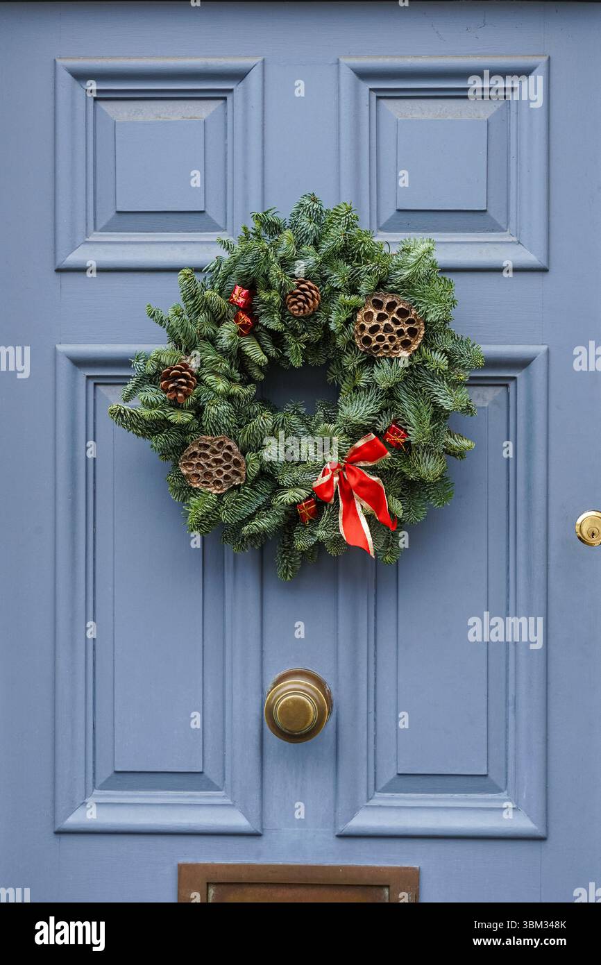La corona decorativa di Natale è appesa su una porta d'ingresso di una casa a Kensington, Londra, Inghilterra, Regno Unito, Regno Unito Foto Stock
