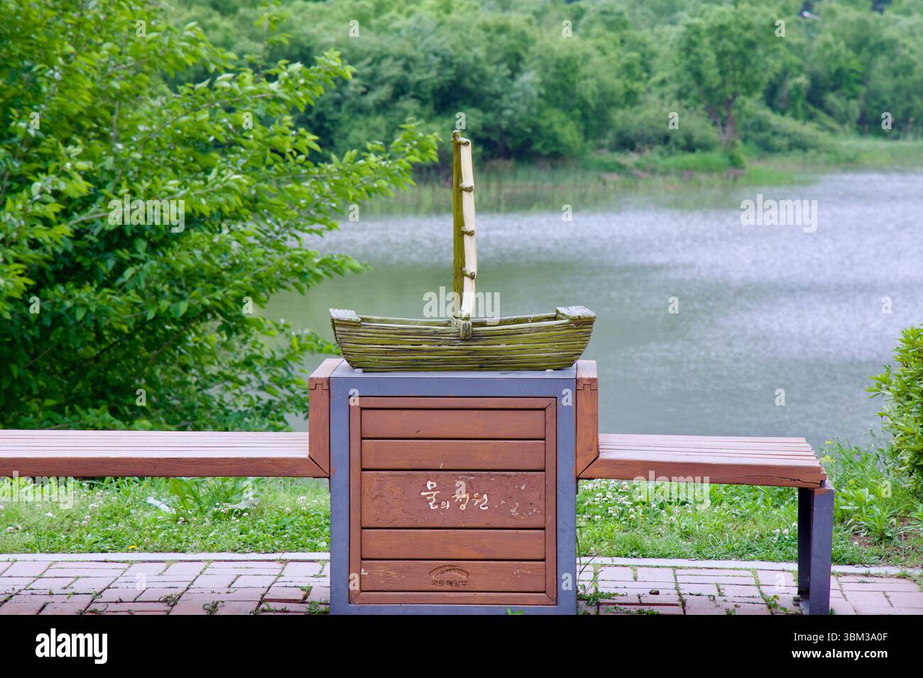 Città di Namyangju, Corea del Sud - 19 maggio 2025: Una piccola scultura di una tradizionale barca in legno si trova in cima a una panchina che si affaccia sulle zone umide di Namyangju Wa Foto Stock