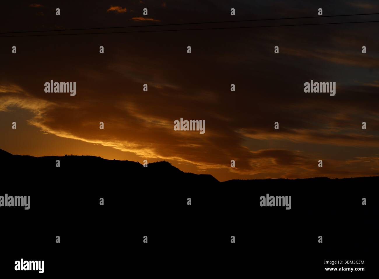 Tramonto dorato sulle silhouette di montagna nel Karoo, Sud Africa. Spettacolare cielo serale con nuvole calde e tranquillo orizzonte rurale. Foto Stock