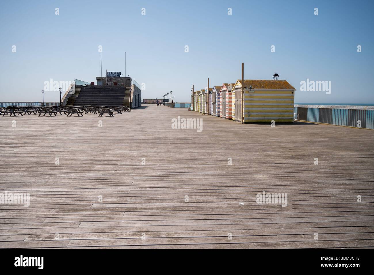 Capanne da spiaggia a strisce gialle e bianche sul molo di Hasstings Foto Stock