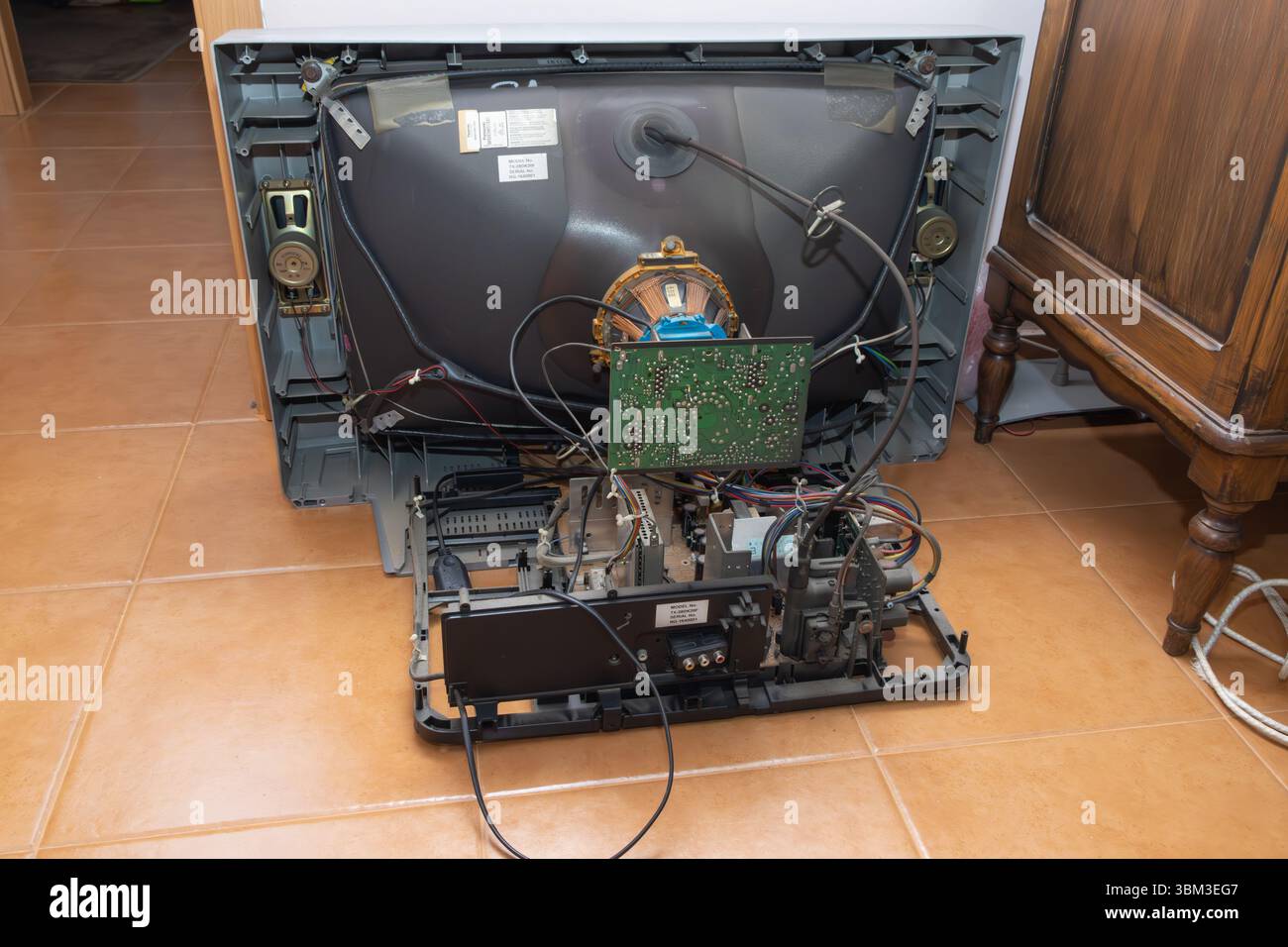 crt tv smontato esponendo i suoi componenti interni, tra cui il tubo catodico, le schede dei circuiti e il cablaggio, suggerendo un processo di riparazione Foto Stock