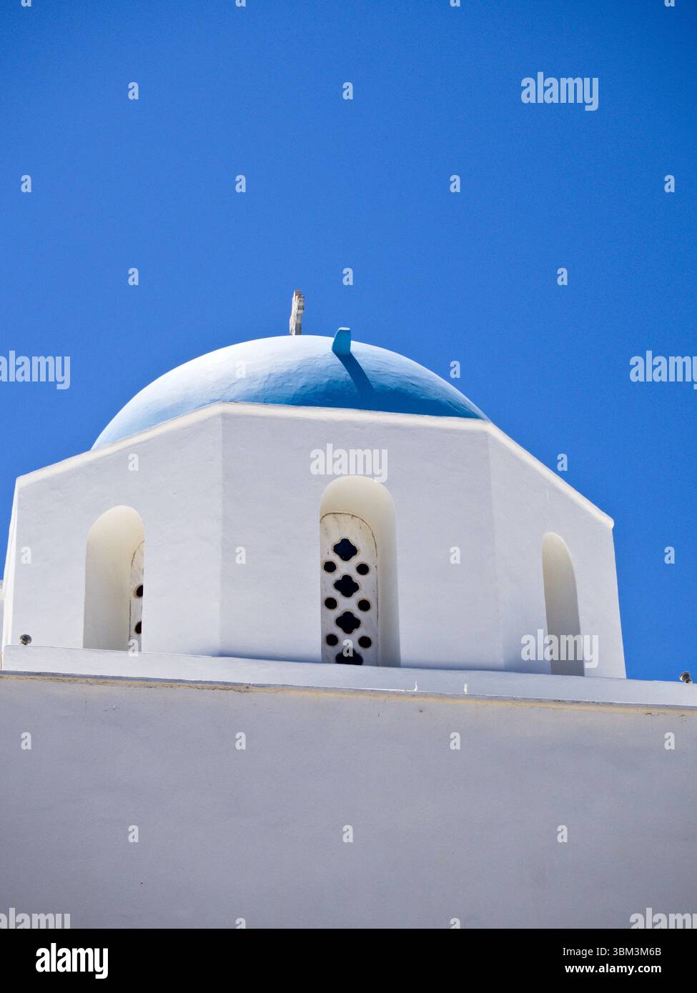 Facciata greca bianca con cupola blu e cielo estivo azzurro, che mostra l'iconica architettura dell'isola delle Cicladi. Foto Stock