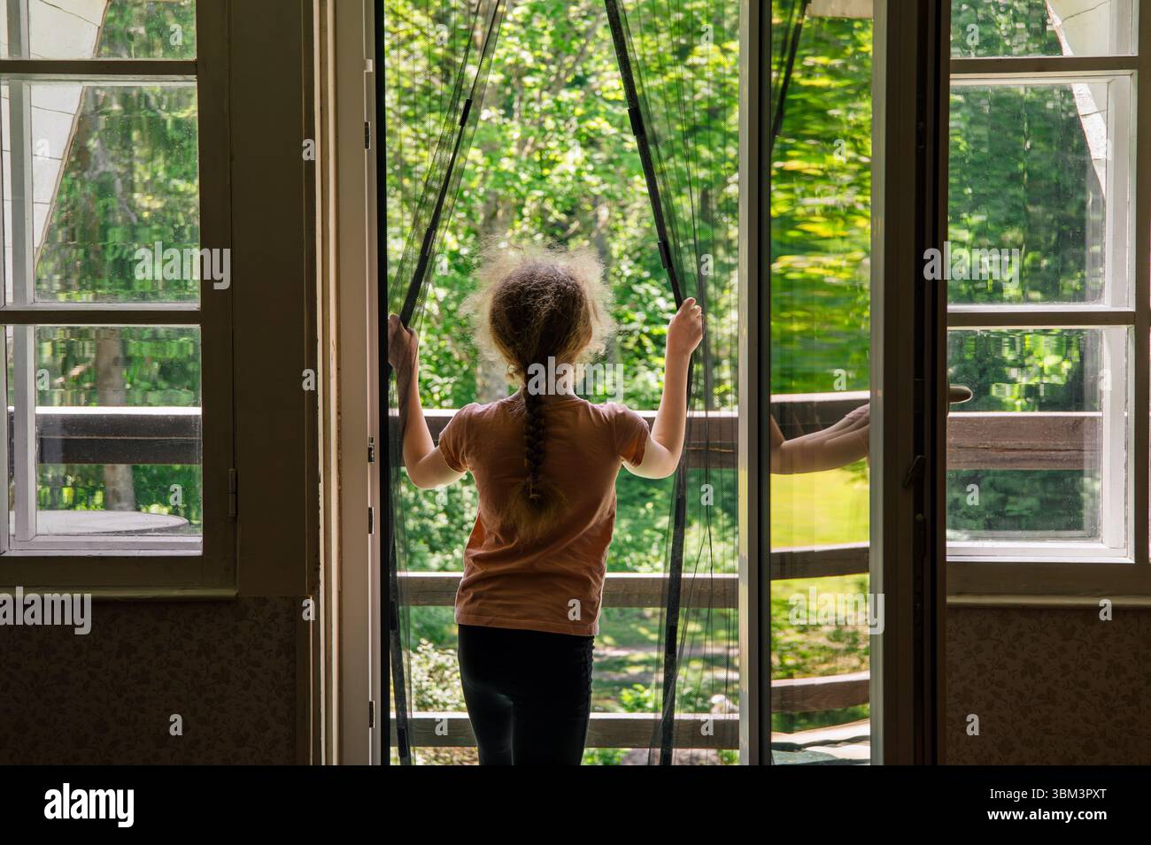 Rete di zanzariere magnetica sulla porta del balcone. Il bambino va all'aperto sul balcone di casa, impedendo l'ingresso degli insetti. Foto Stock