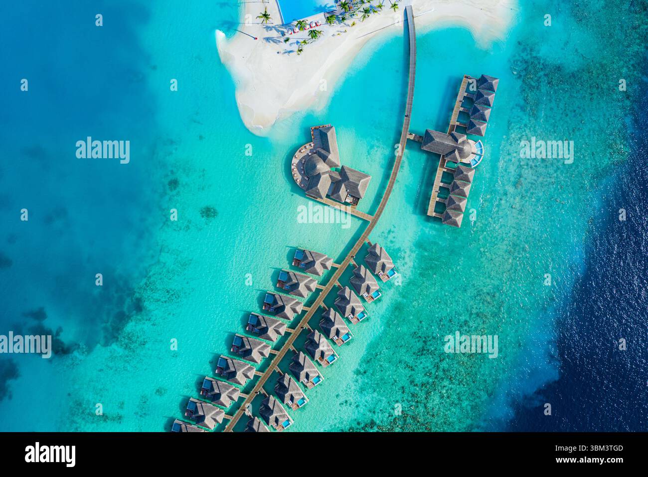 Incredibile vista aerea delle ville sull'acqua delle Maldive, che mostra il resort tropicale dell'isola, il mare turchese, la spiaggia sabbiosa e il cielo blu, una perfetta vacanza estiva Foto Stock