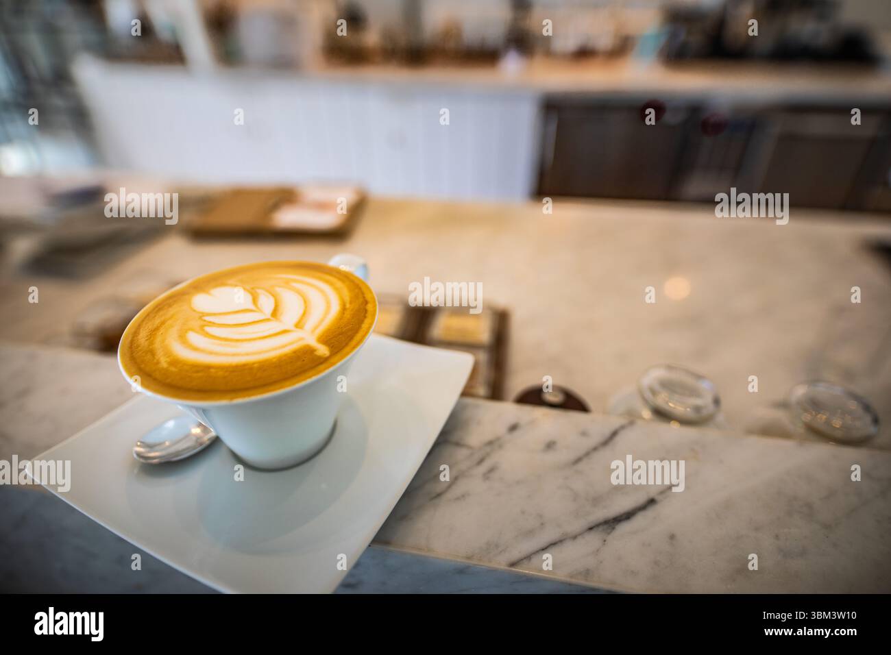 Latte art su banco in marmo in un elegante caffè con morbido sfondo sfocato, elegante ambiente interno caffetteria per il relax, moderno concetto di bevande Foto Stock