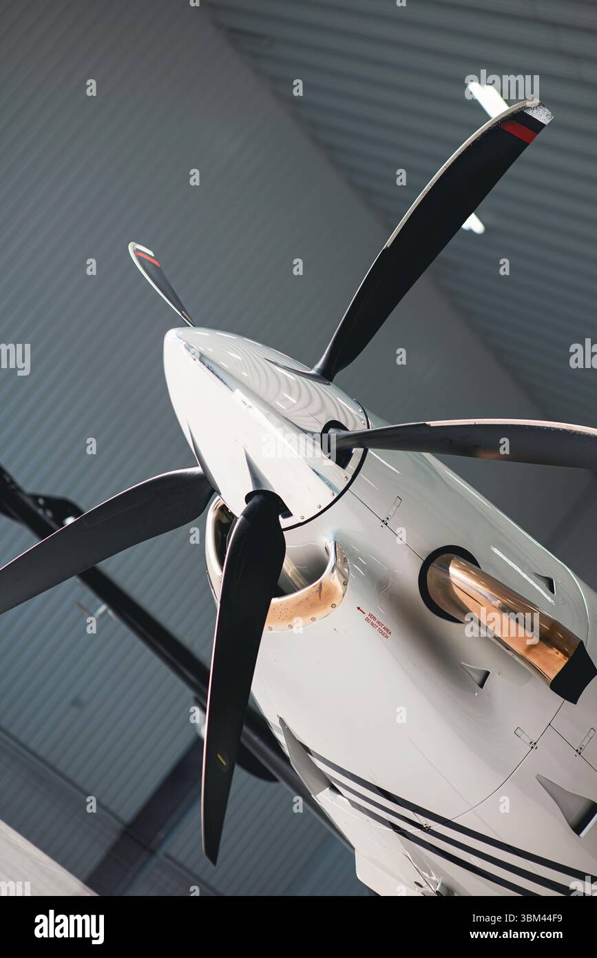 Primo piano angolato di un velivolo a turboelica e di un'elica all'interno di un hangar dell'aereo, che mostra dettagli in metallo lucido e scarico. Foto Stock