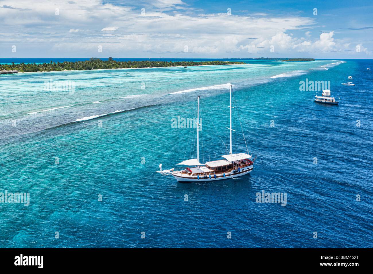 Il paesaggio aereo della spiaggia con lo yacht bianco, immersioni subacquee nella baia laguna dell'oceano tropicale delle Maldive, sopra la splendida barriera corallina, acque turchesi esotiche Foto Stock