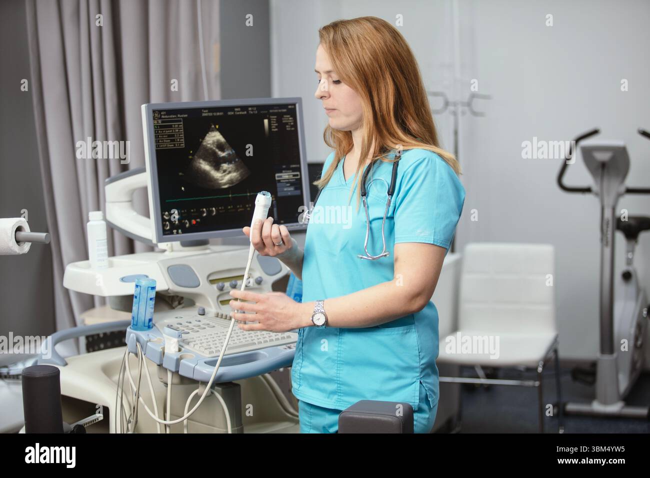 Сardiologist nel suo ufficio vicino a dispositivi medici. Un medico di riabilitazione in un centro medico vicino ai moderni dispositivi medici in attesa di un paziente. Foto Stock