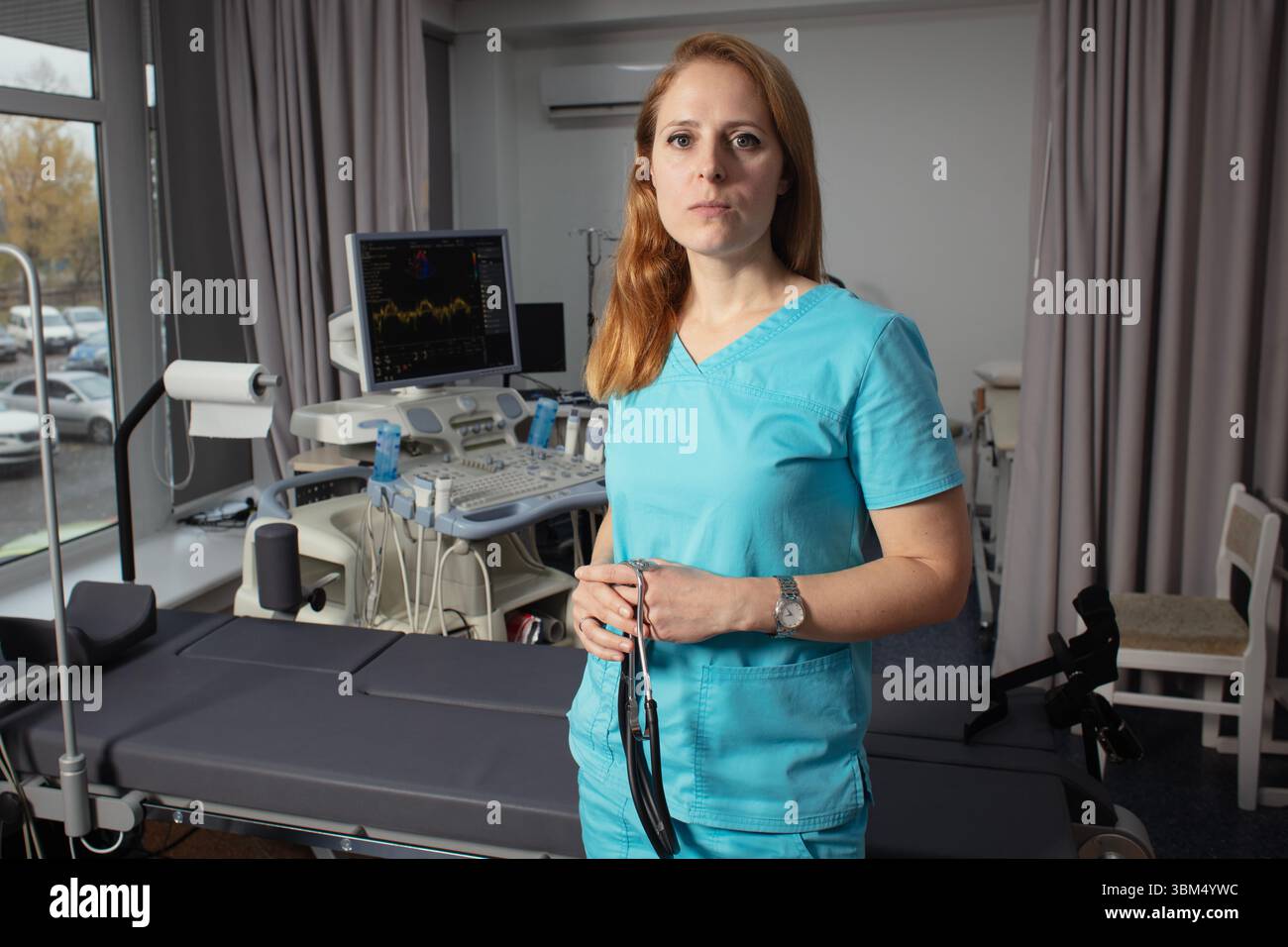 Сardiologist nel suo ufficio vicino a dispositivi medici. Un medico di riabilitazione in un centro medico vicino ai moderni dispositivi medici in attesa di un paziente. Foto Stock