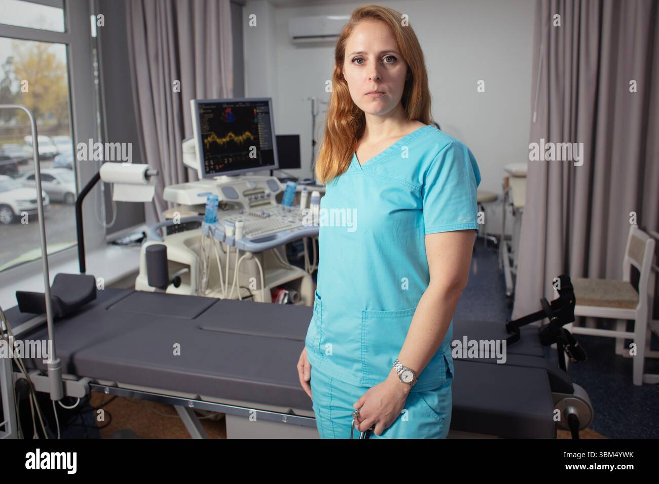 Сardiologist nel suo ufficio vicino a dispositivi medici. Un medico di riabilitazione in un centro medico vicino ai moderni dispositivi medici in attesa di un paziente. Foto Stock