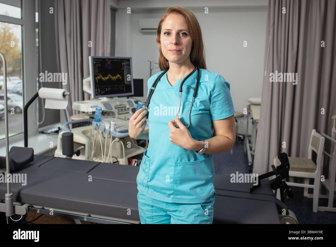 Сardiologist nel suo ufficio vicino a dispositivi medici. Un medico di riabilitazione in un centro medico vicino ai moderni dispositivi medici in attesa di un paziente. Foto Stock
