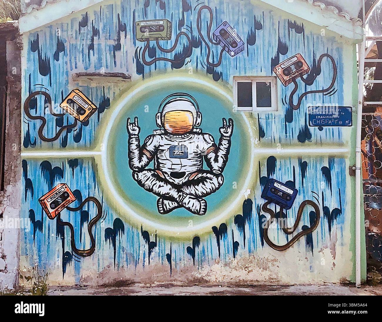 La vivace Street art di Tulum, Messico, presenta un astronauta circondato da colorate cassette retrò in un cosmico pop mashup. Foto Stock