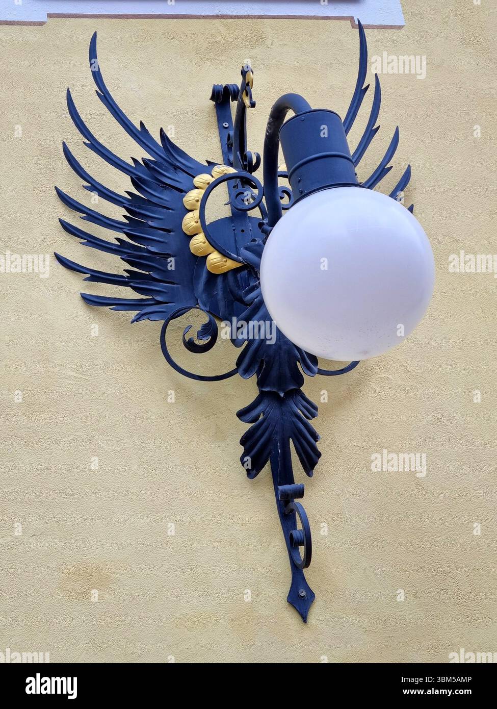 Vista di una lanterna in ferro battuto a forma di drago stilizzato con elemento dorato sul muro di un edificio nella località alpina di Ortisei Foto Stock