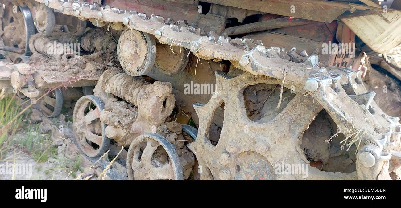 Il trattore cingolato per impieghi gravosi effettua manovre su campi fangosi, mostrando il suo design robusto. L'attrezzatura è impegnata in lavori agricoli, preparando il Foto Stock