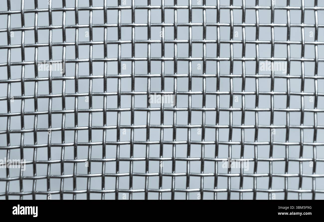 Vista dettagliata dei fili metallici interconnessi che formano un modello a griglia in una disposizione geometrica, mostrando il design industriale e la simmetria strutturale Foto Stock