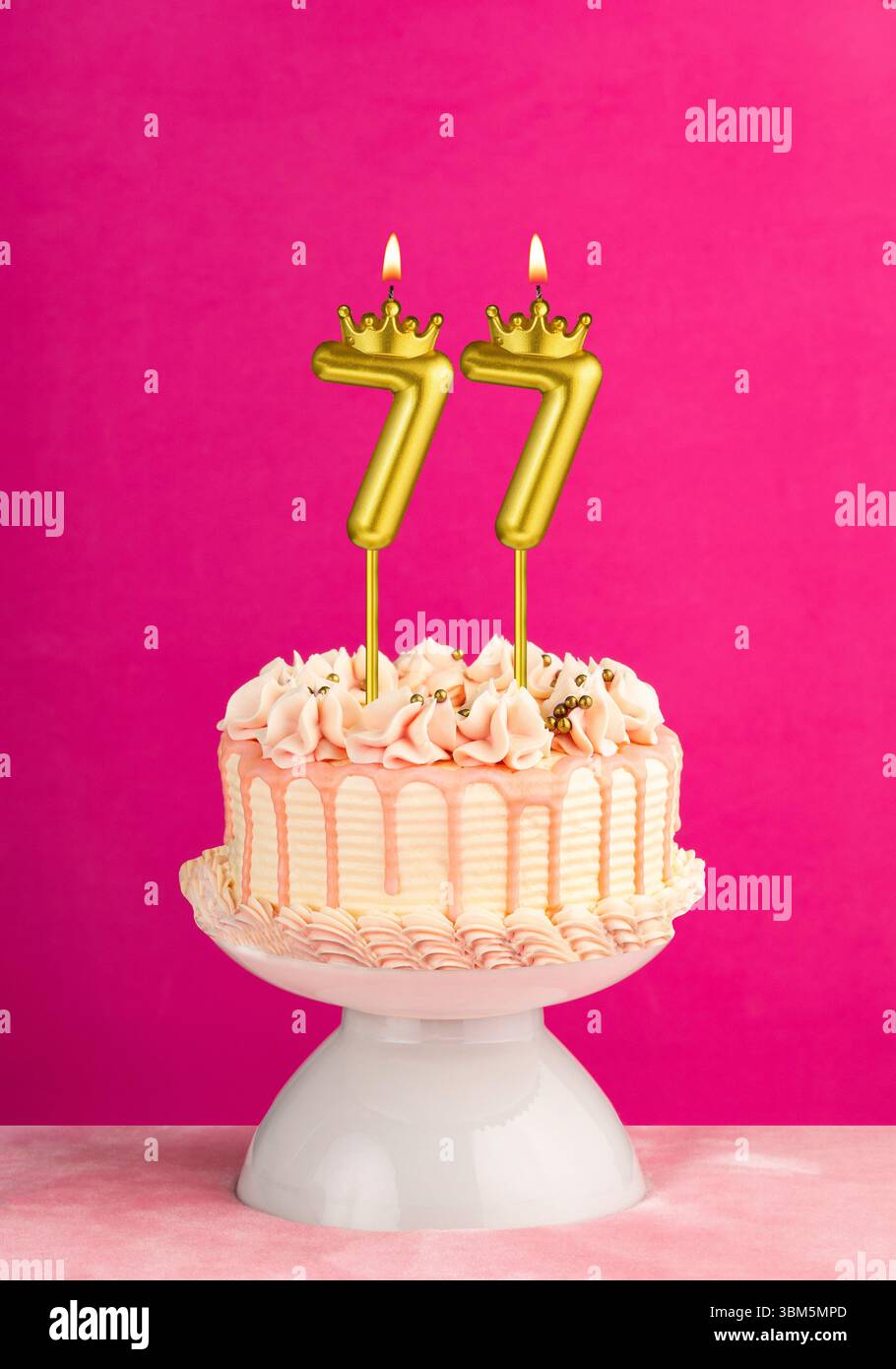 Candela di compleanno numero 77 - torta rosa per festeggiare con glassa a goccia Foto Stock