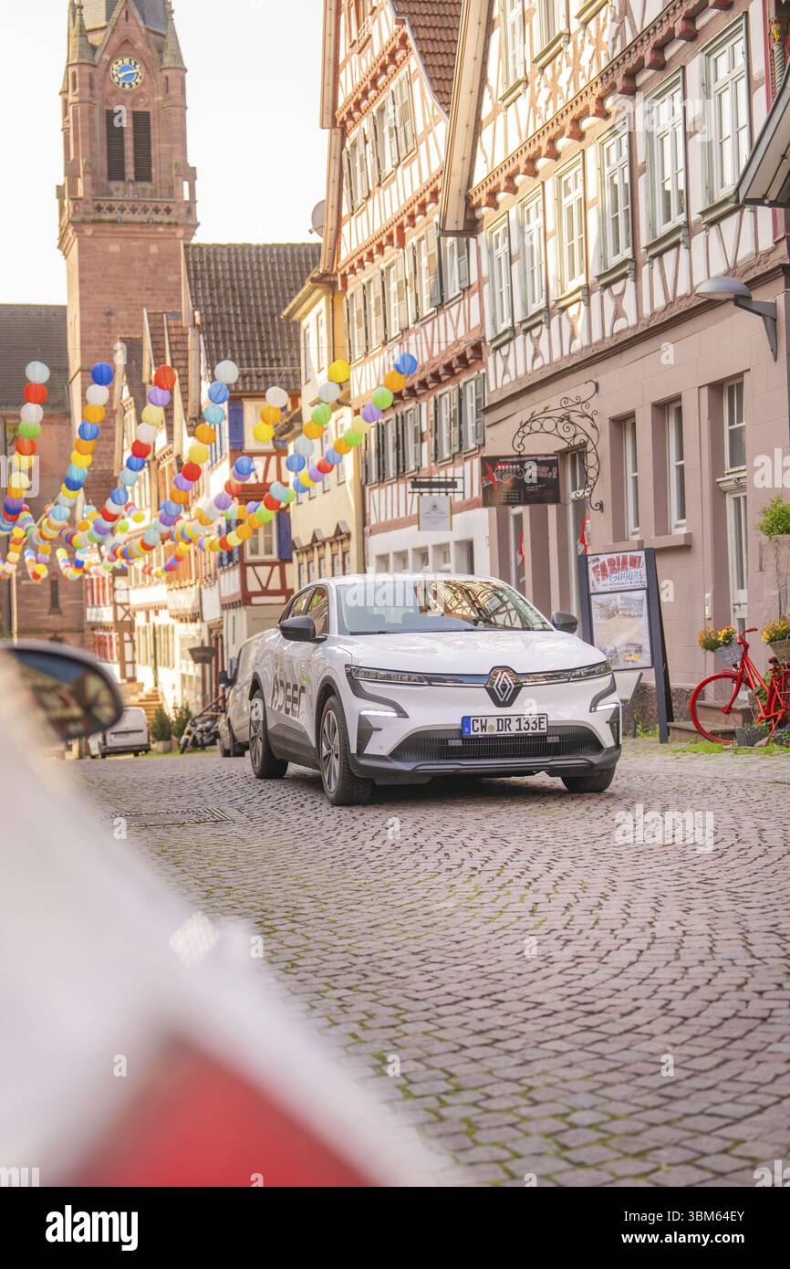 Un'auto elettrica bianca parcheggiata su una strada acciottolata decorata con palloncini nel centro storico della città, Deer e, car sharing, auto elettrica, Calw, foresta Nera Foto Stock