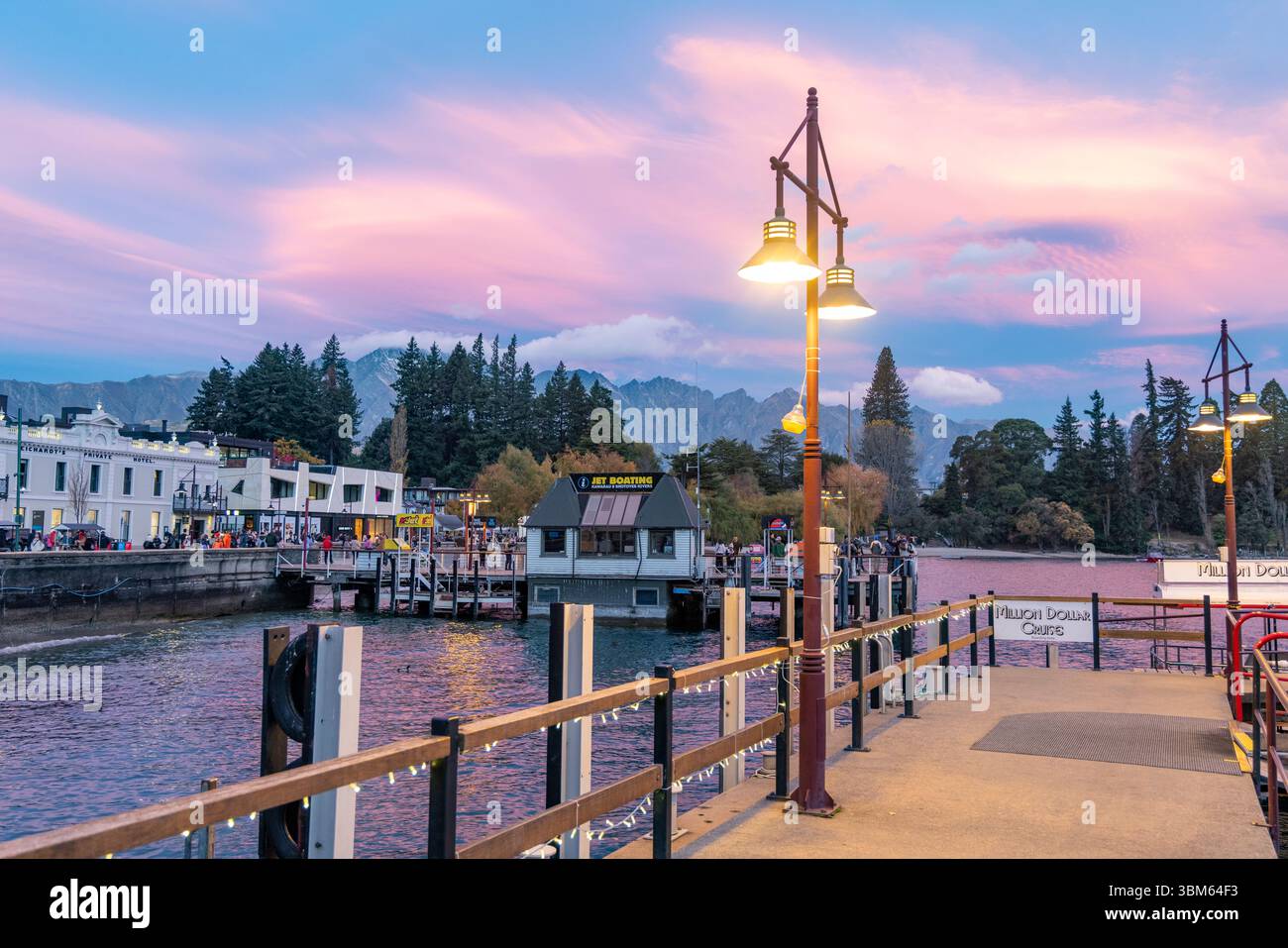Queenstown Sunset, Queenstown Wharf e centro città con lampioni sul Lago Wakatipu, regione di Otago, Isola del Sud, nuova Zelanda Foto Stock