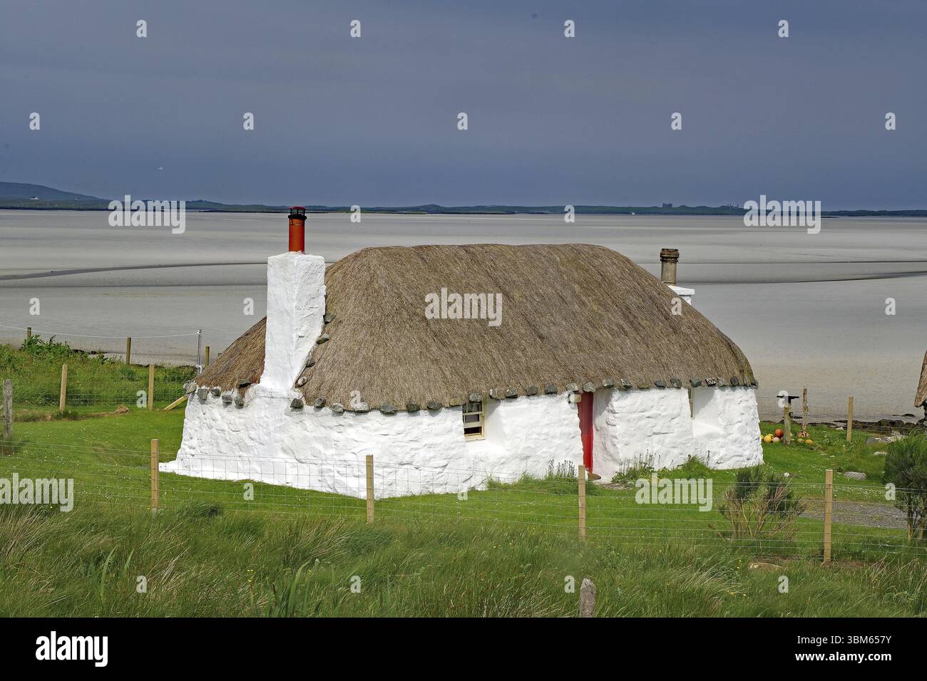 Casa di paglia bianca su un prato verde su uno sfondo costiero sabbioso sotto un cielo blu, vacanze, casa per le vacanze, North Uist, Ebridi, Scozia, GRE Foto Stock