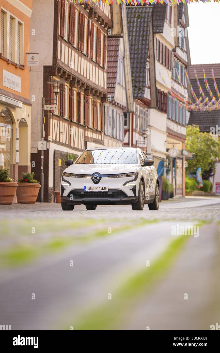 Un'auto bianca attraversa una strada con case a graticcio e decorazioni colorate in una città vecchia, Deer e, car sharing, auto elettrica, Calw, nero Foto Stock