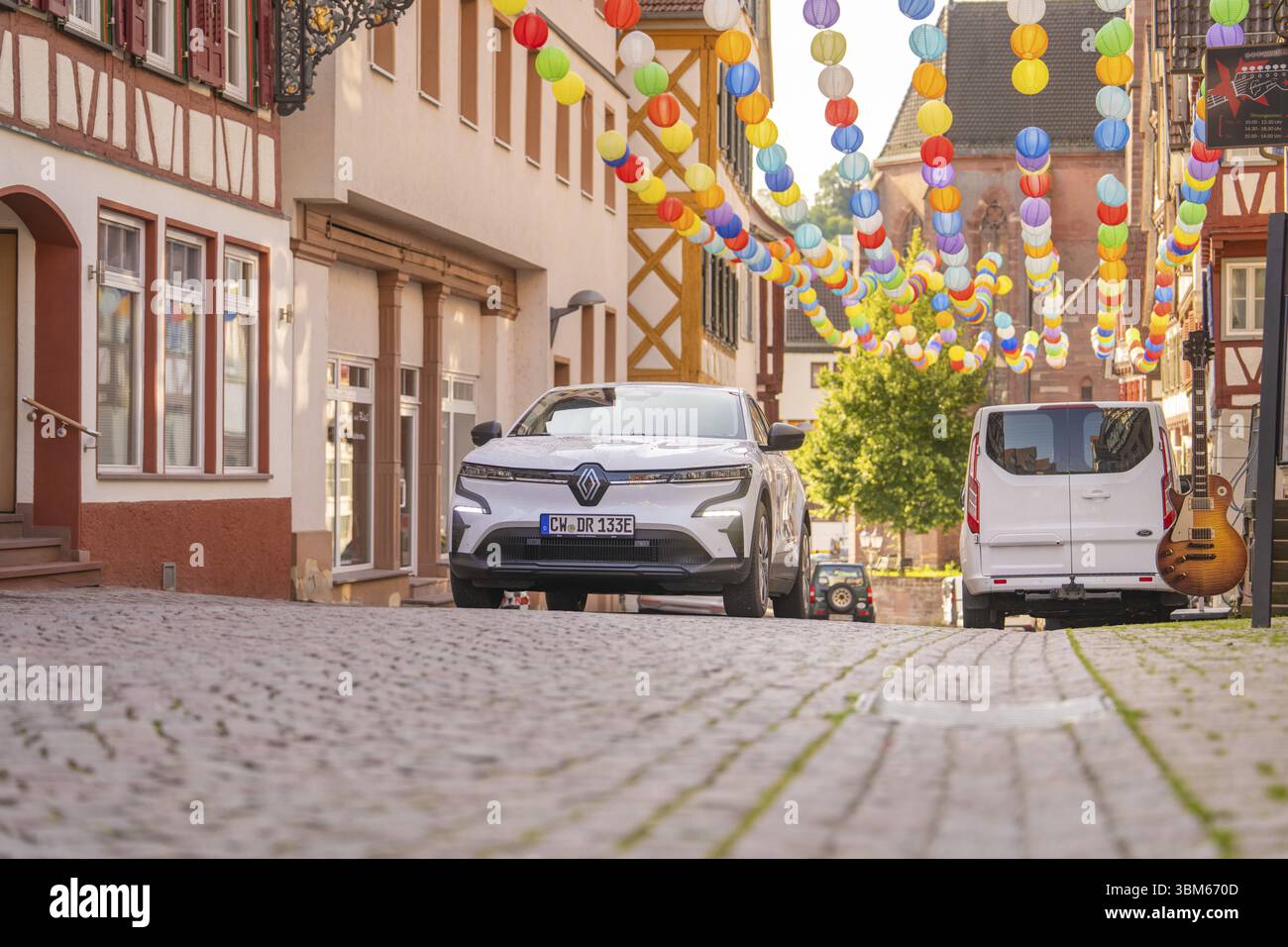 Auto bianca in un vicolo decorato con lanterne colorate sotto un cielo blu, cervi e, car sharing, auto elettrica, Calw, foresta Nera Foto Stock