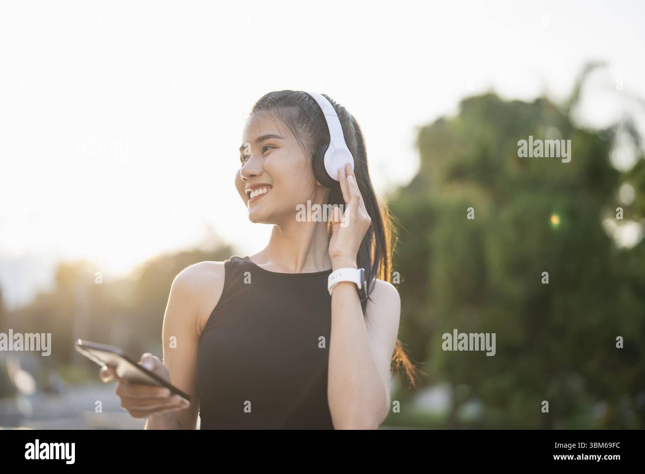 Felice attiva sana donna asiatica ascoltare musica con cuffie per la salute mentale ascoltare audio per l'ispirazione corsa Foto Stock