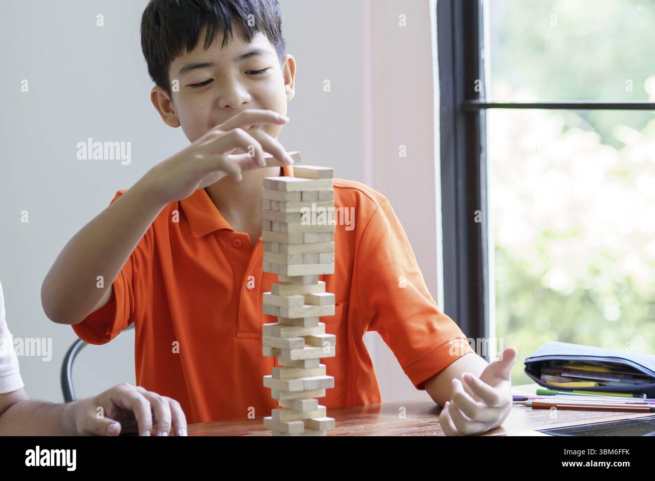 Padre e figlio asiatici che giocano a blocchi di legno gioco Carefree ragazzo che gioca blocchi di legno costruttore di costruzioni di gioco da blocchi con padre a casa Foto Stock