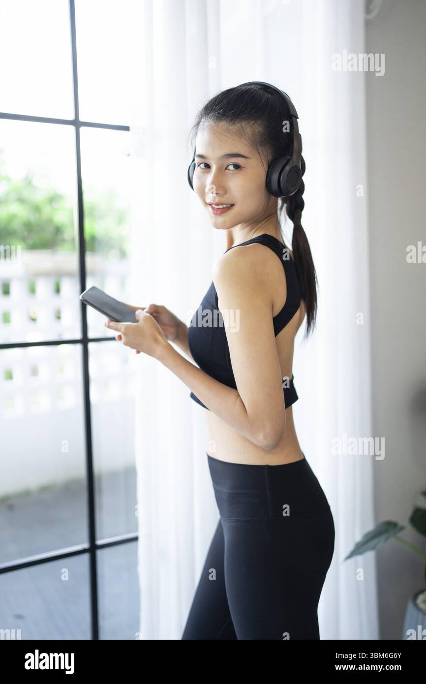 Fitness donna asiatica che utilizza smartphone e cuffie si diverte ad ascoltare musica. Donna con cuffie per smartphone dopo l'allenamento Foto Stock