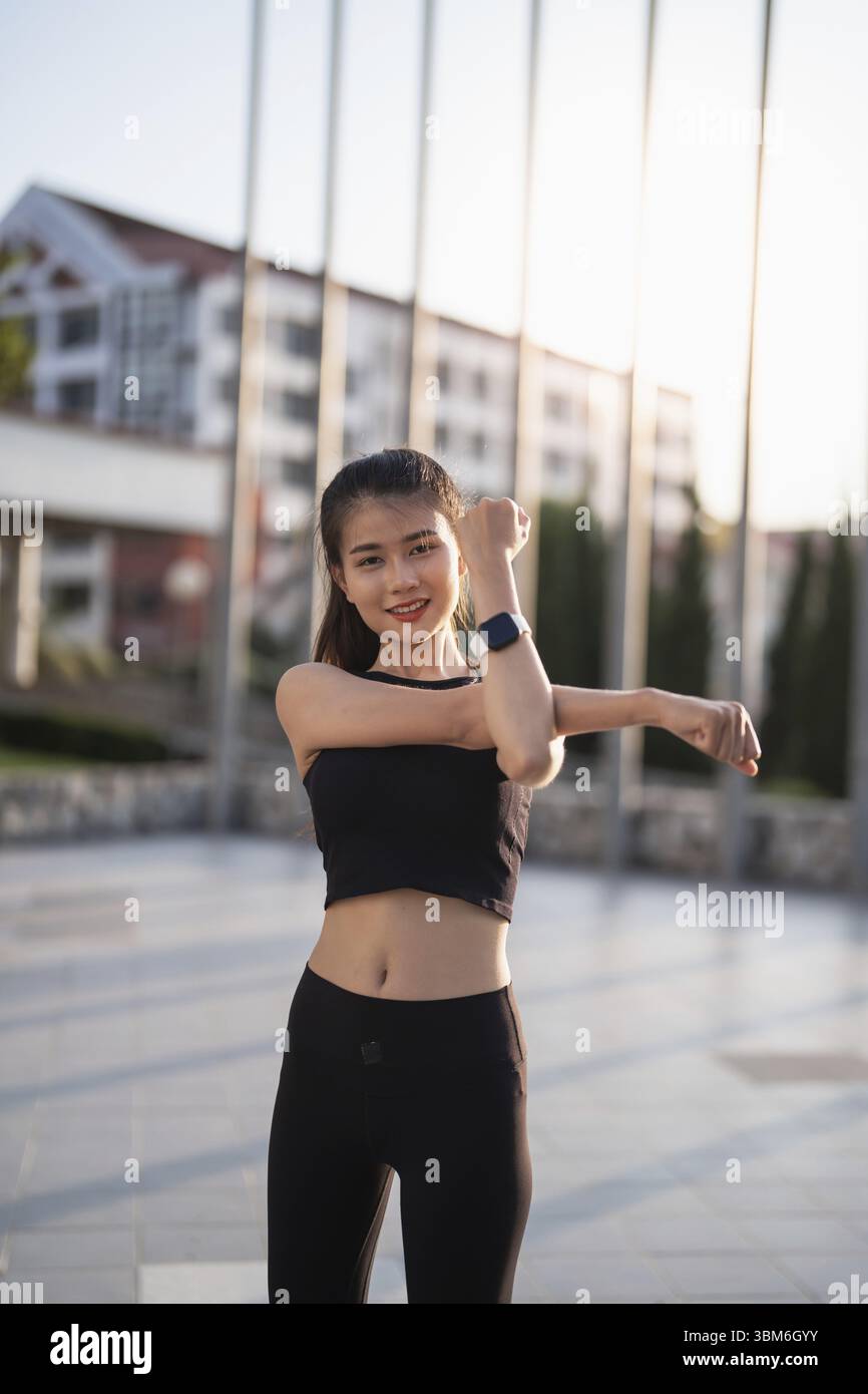 Attiva donna asiatica sana che esercita atleti in abiti fitness Sunrise sport ragazza davanti alla città motivazione per uno stile di vita sano Foto Stock