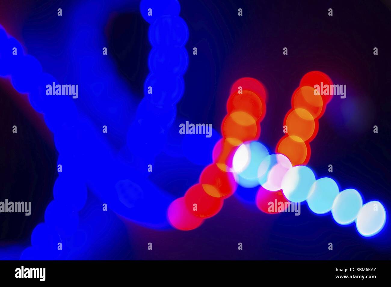 Ricci sfocati al neon rosso e blu di luci bokeh sul nero. Sfondo astratto con colori di 80 secondi Foto Stock