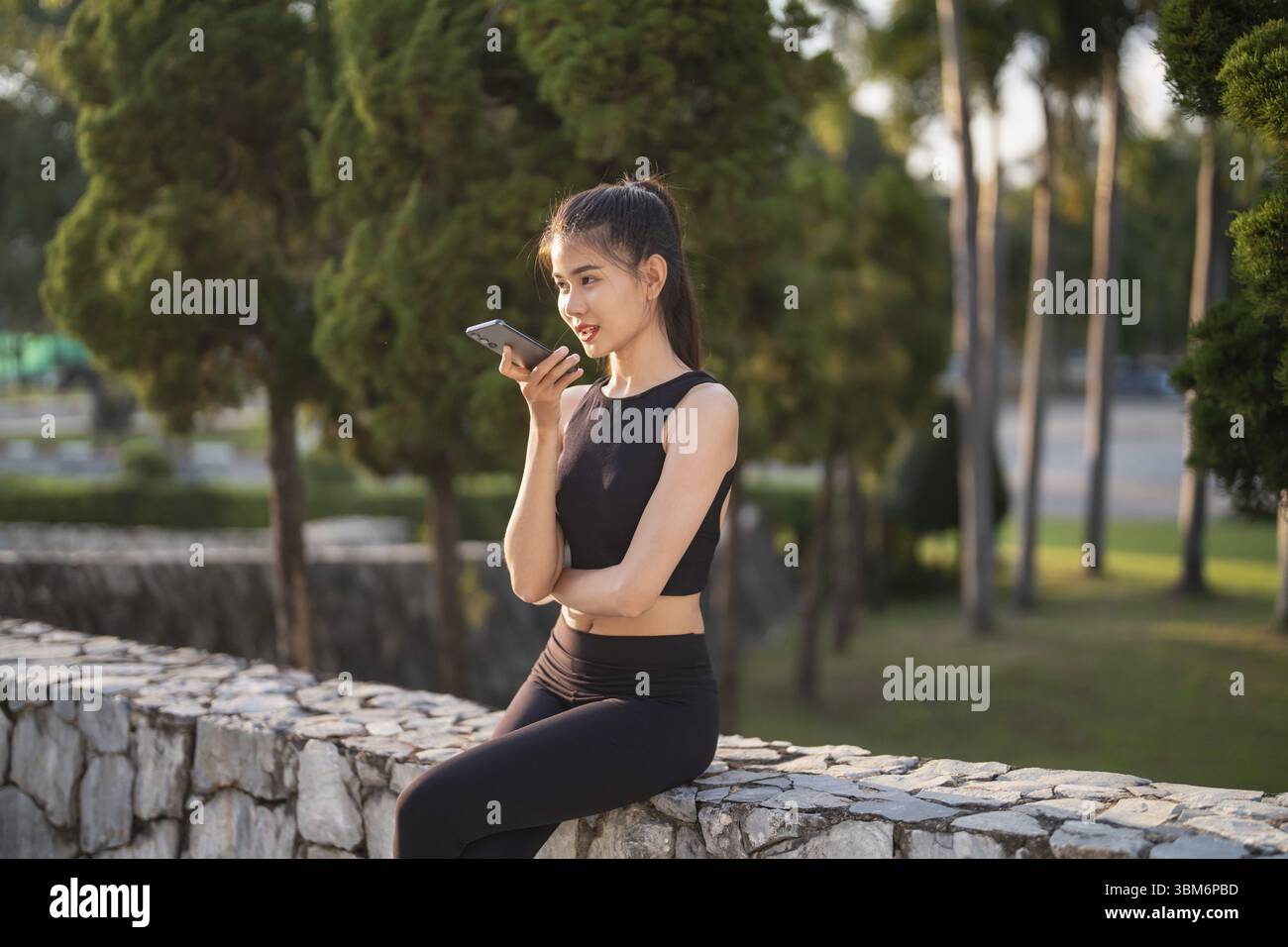 Donna asiatica che utilizza l'assistente vocale su smartphone conversazione con assistente online bot chat vocale intelligenza artificiale conversazionale tecnologie moderne Foto Stock