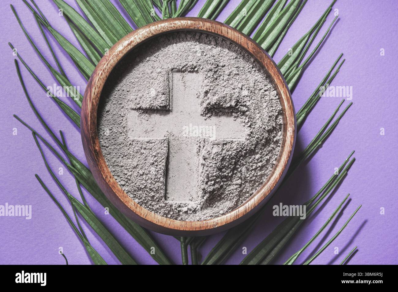 Schale mit Kreuzaufdruck in grauer Asche auf lila Hintergrund. Aschermittwoch Foto Stock