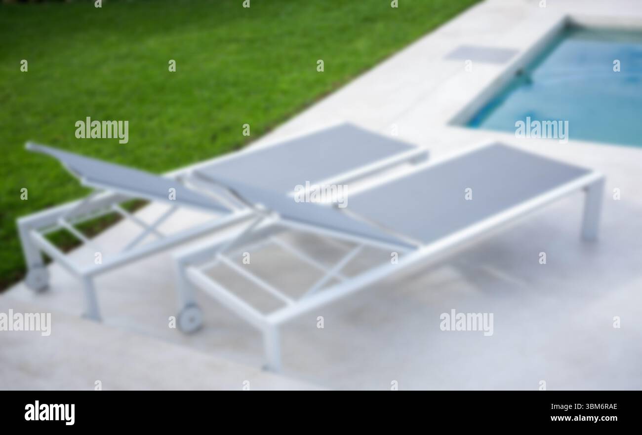 Sedie a sdraio vuote vicino alla piscina nel cortile Foto Stock